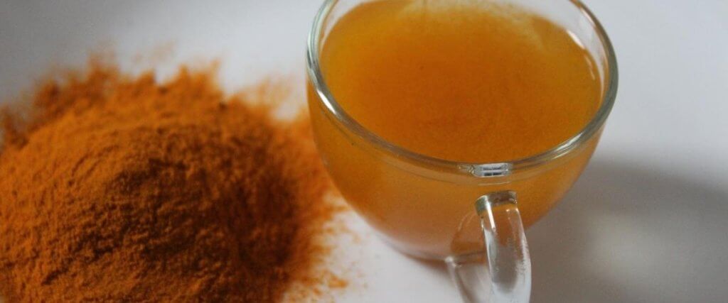 a cup of turmeric water with powder